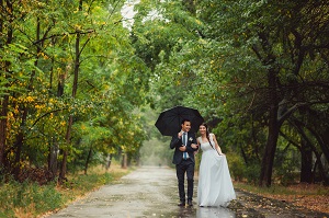 bride and groom walking under umbrella